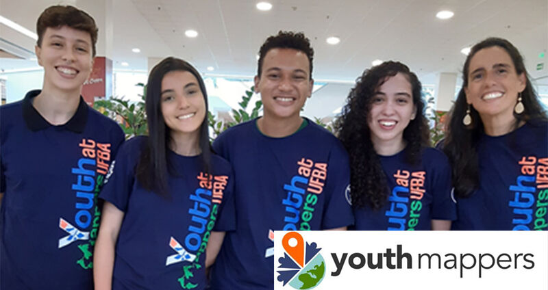 5 young people in YouthMappers shirts smile for a picture.